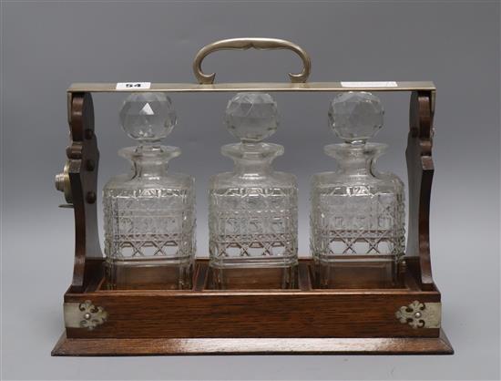 An early 20th century oak three bottle tantalus W.36cm